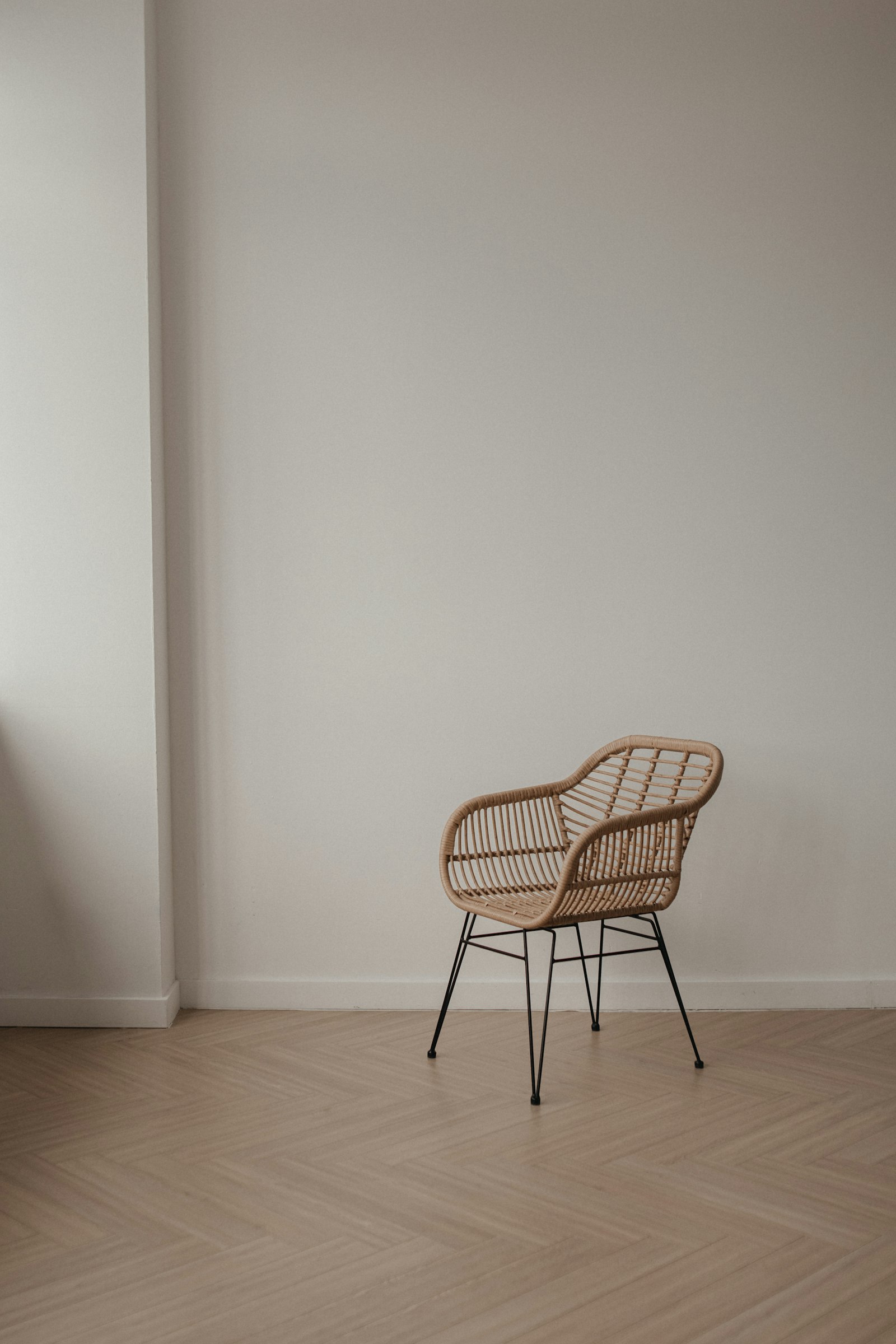 Rattan armchair on black steel legs in an empty white room