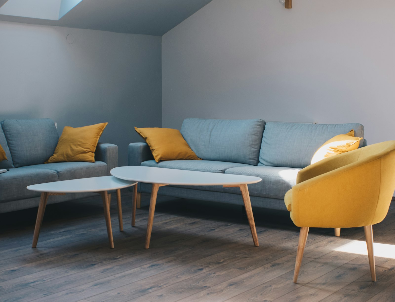 Blue sofa with mustard cushions and white coffee tables