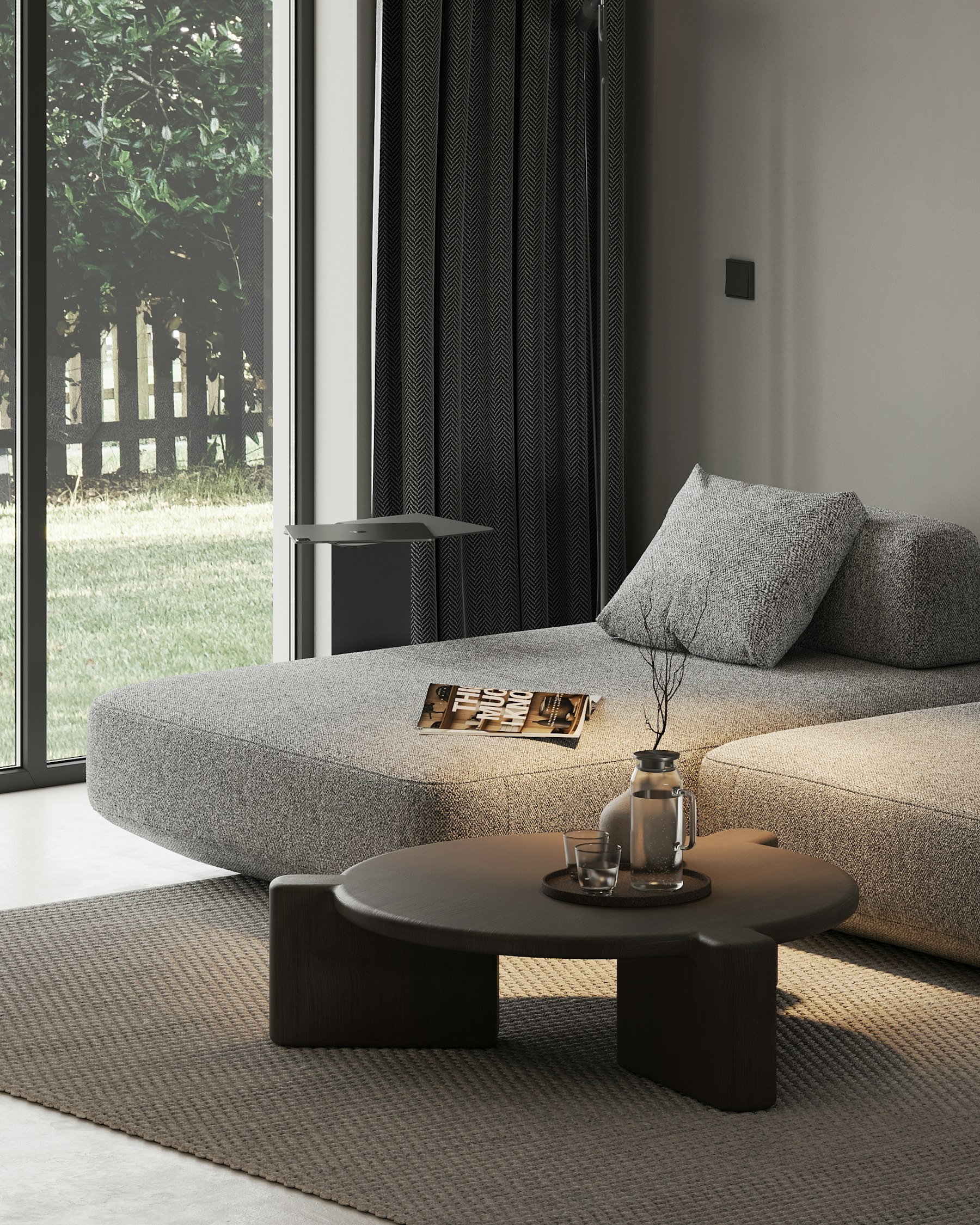 Low grey modular sofa and round black table by a garden window