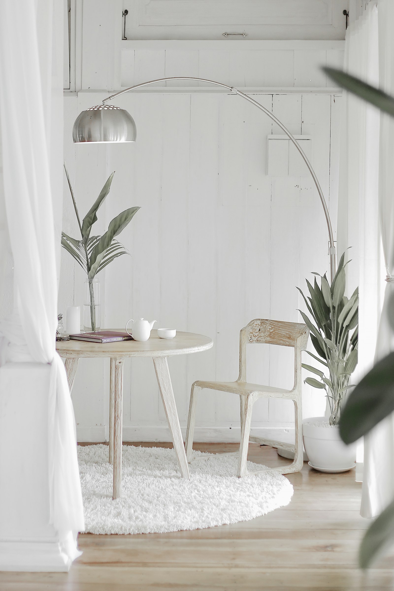 Round white table and chair by sheer curtains
