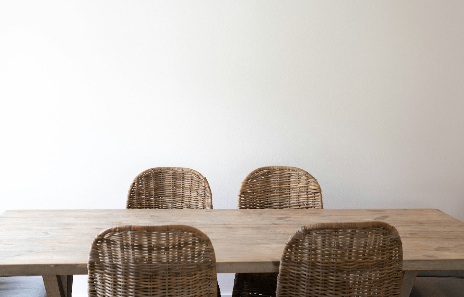 Wicker dining chairs around a pale wooden table
