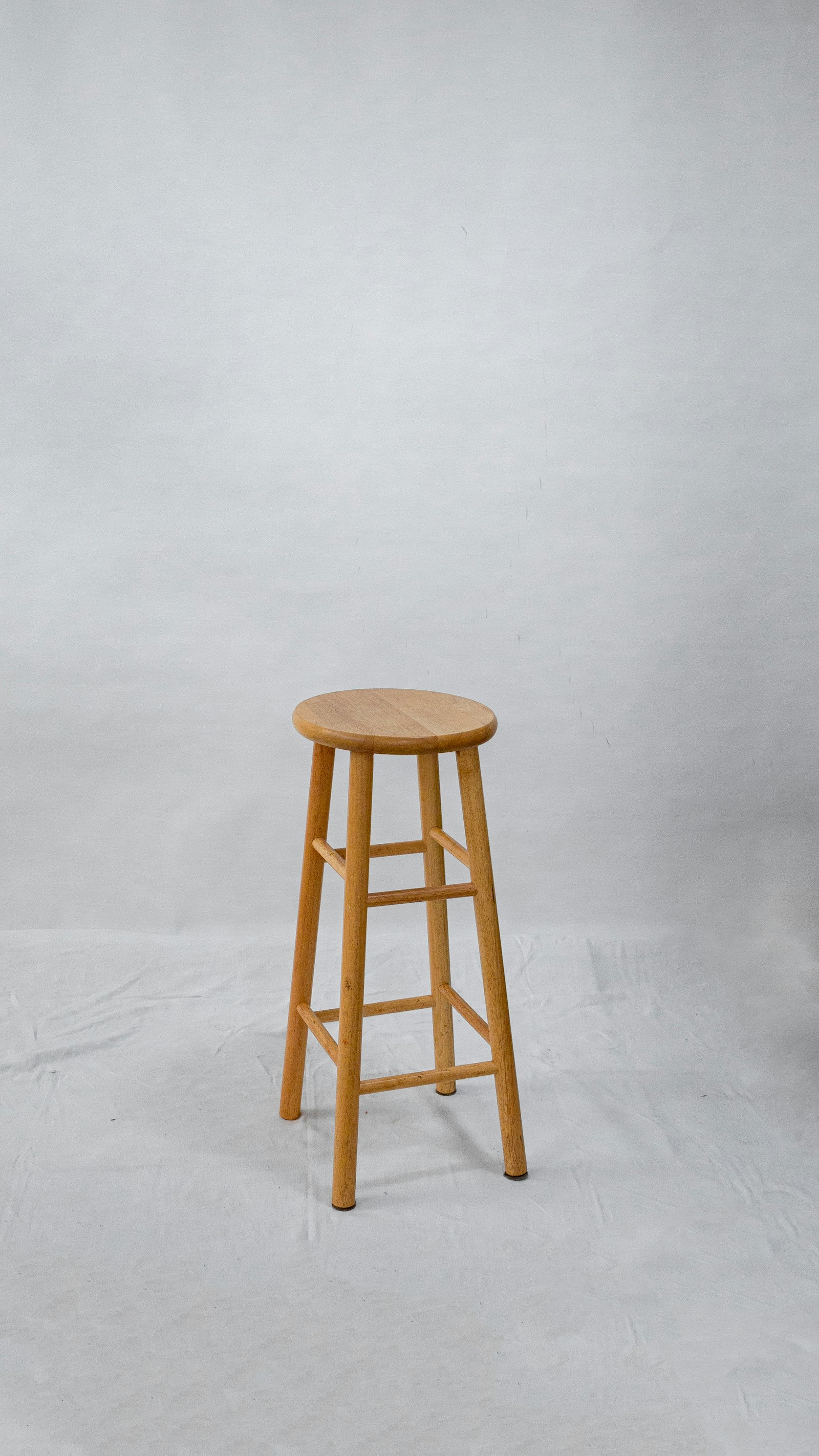 Tall oak bar stool against a grey wall